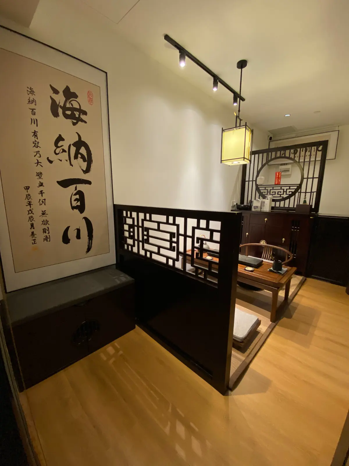 A calligraphy scroll and paper lantern above the carved timber partition