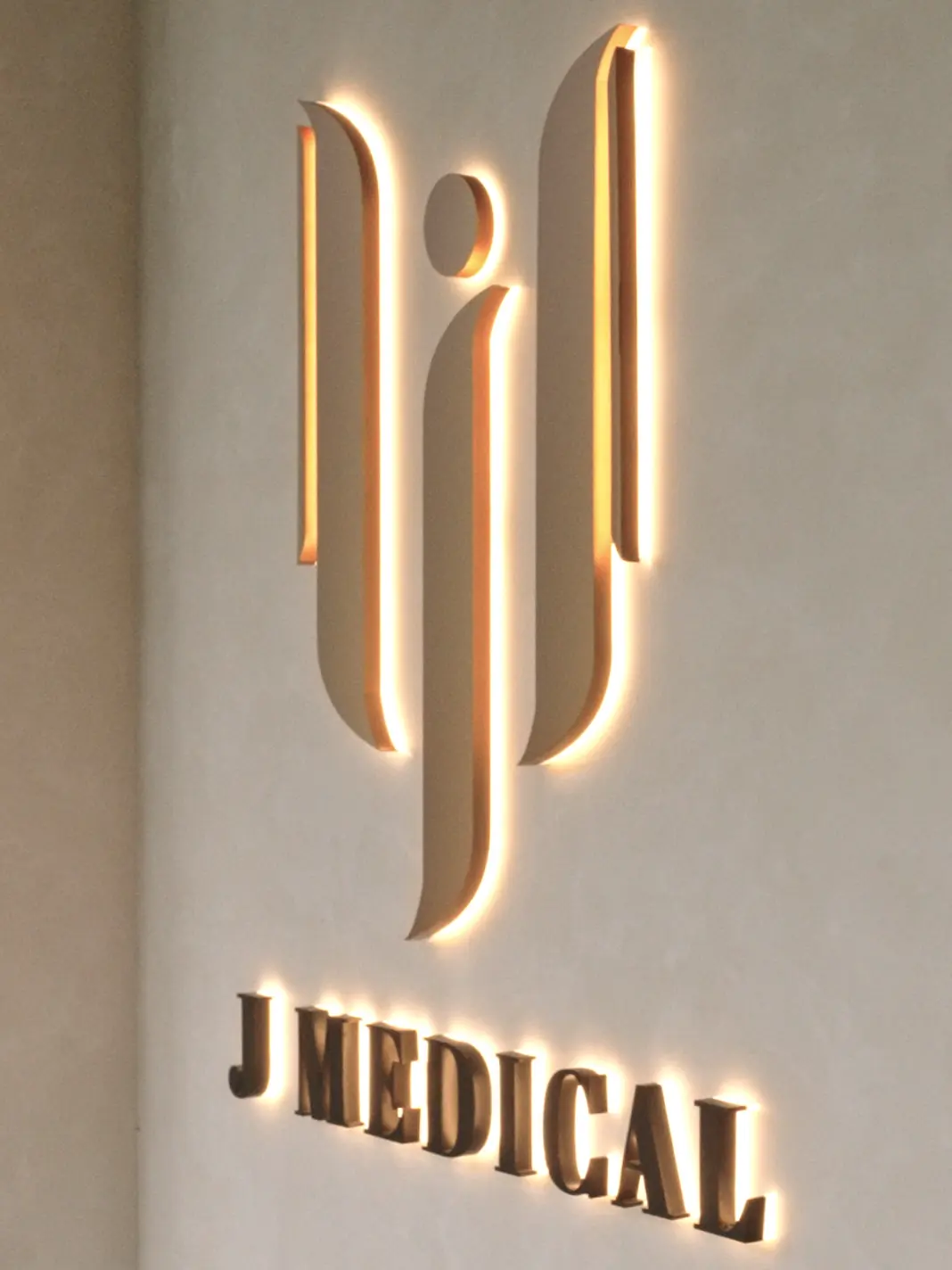 The J Medical monogram, backlit against microcement