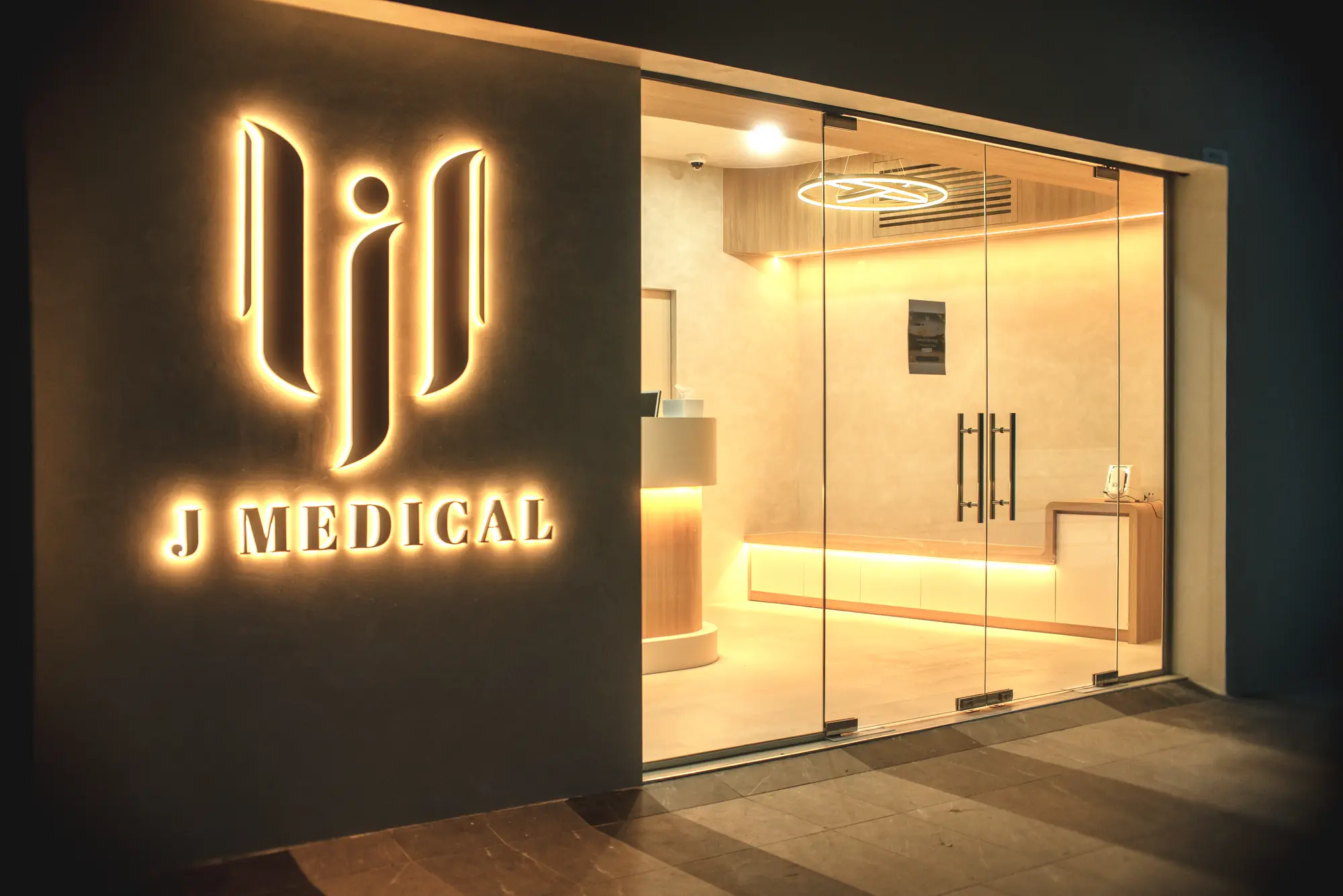 The dark microcement shopfront with its backlit brass logo