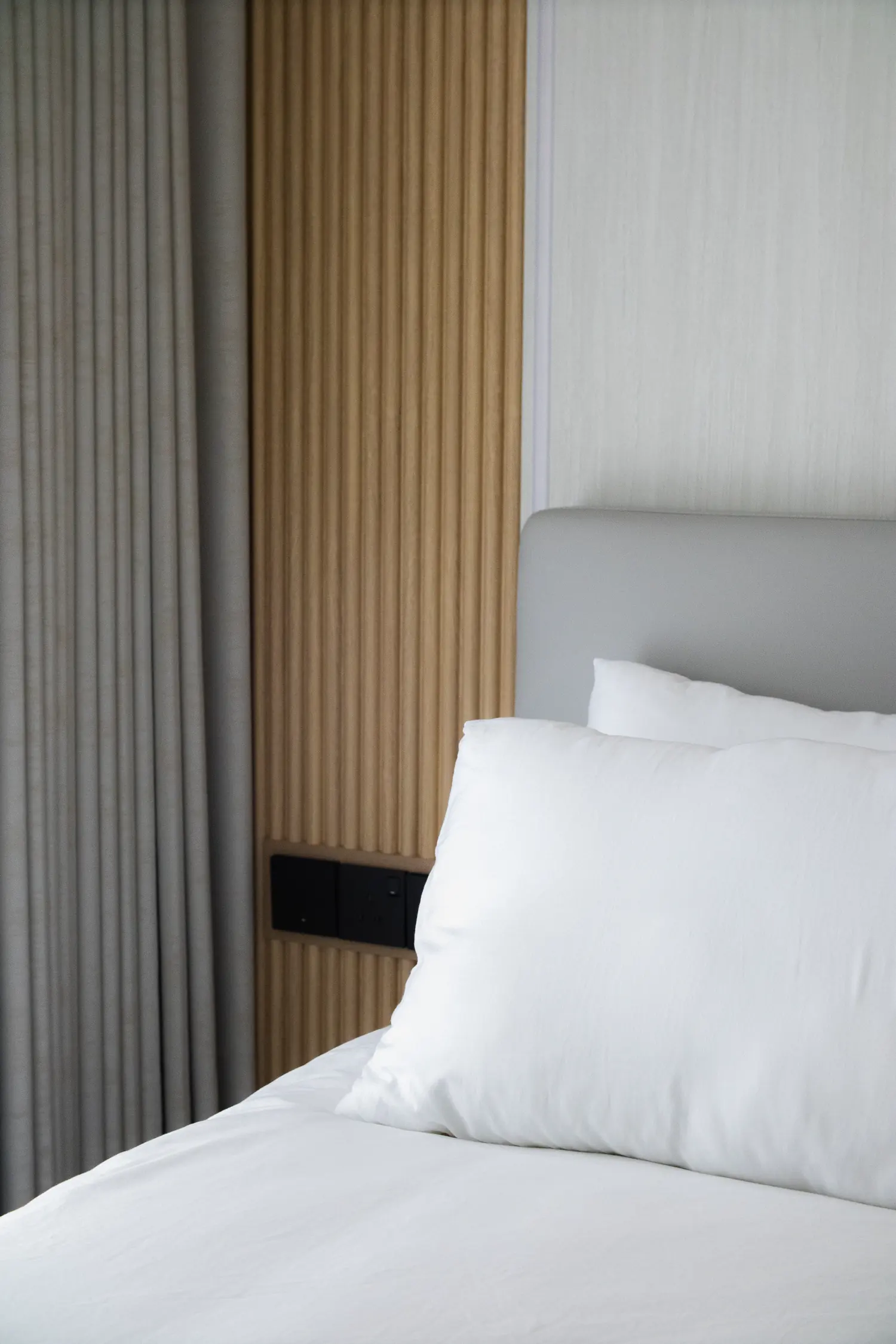 Fluted oak panelling behind the bed, textured wallcovering alongside